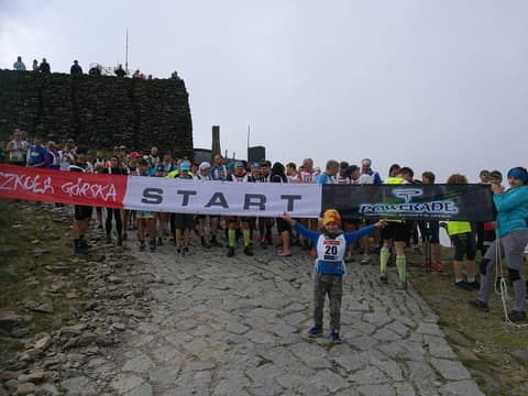 Leon z numerem startowym przed banerem START biegu górskiego