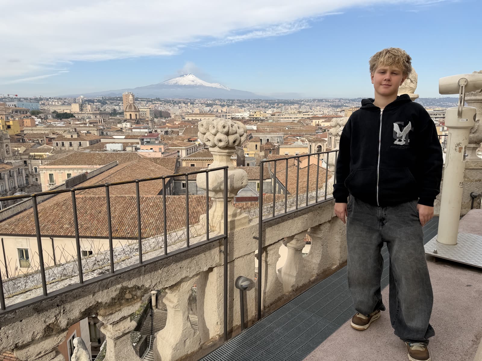 Leon na tarasie w Katanii, w tle ośnieżona Etna