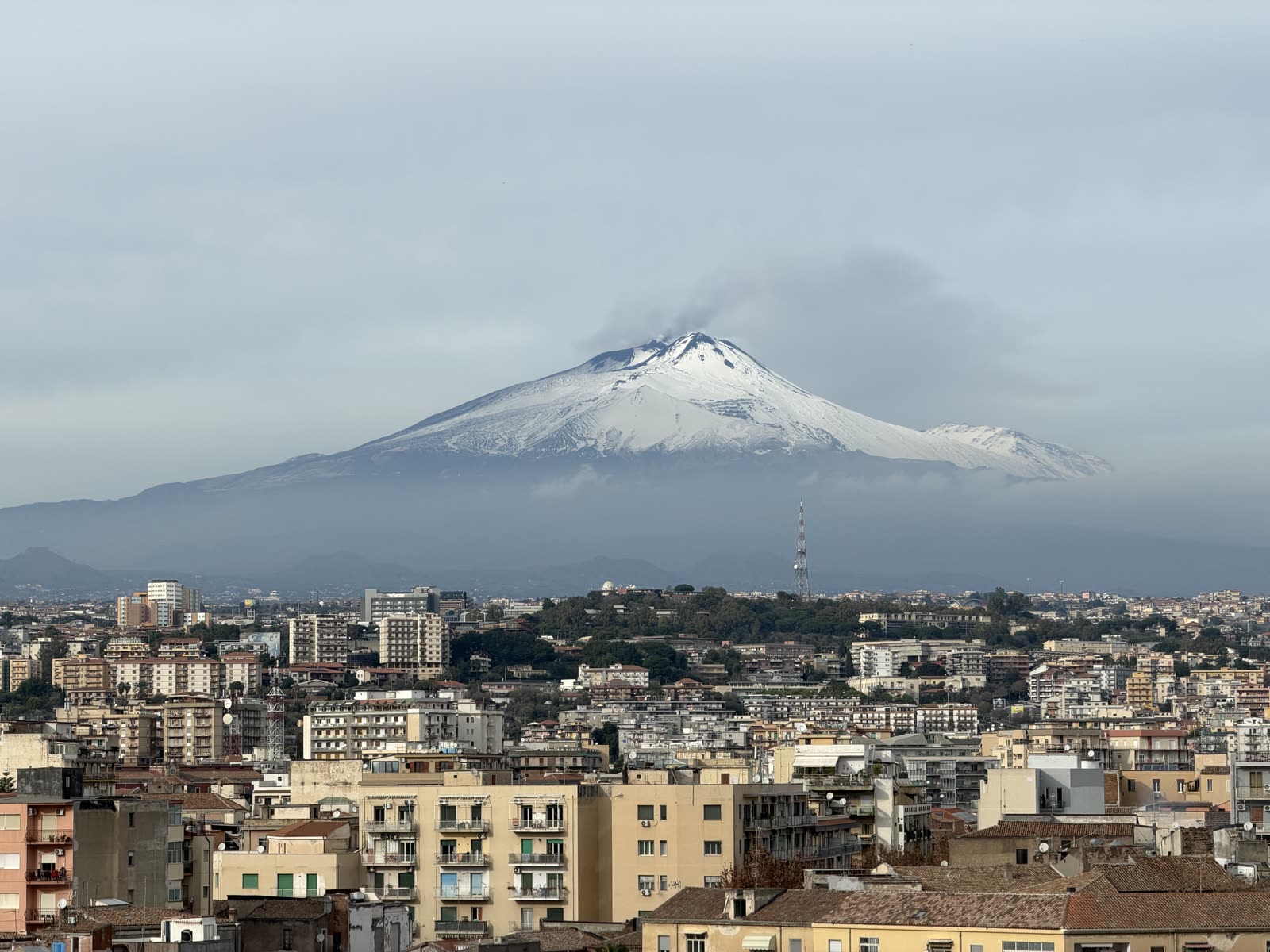 Ośnieżona Etna górująca nad dachami Katanii