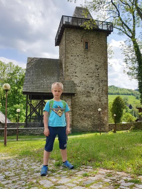 Leon przed kamienną wieżą z drewnianym gankiem