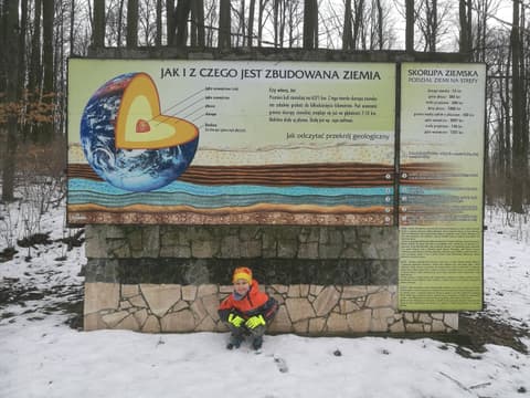Leon pod tablicą o budowie Ziemi przy ścieżce dydaktycznej