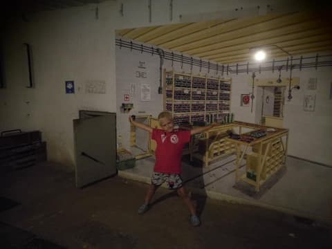 Leon z rozłożonymi rękami w podziemnej sali z regałami