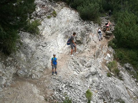 Leon na skalistym trawersie razem z innymi turystami