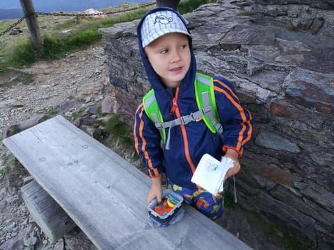 Leon z kartką w ręku na kamiennej ławie przy szlaku