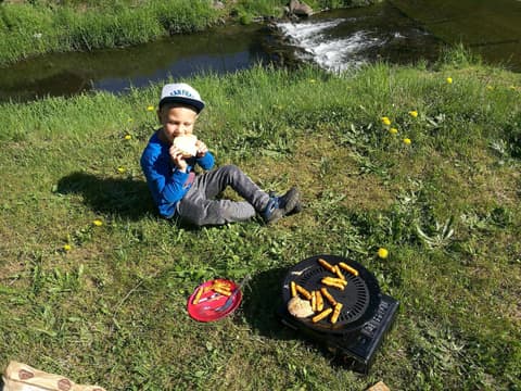 Leon je bułkę nad potokiem, obok turystyczny grill