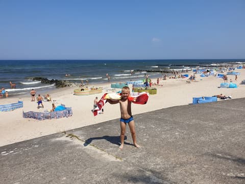 Leon biegnie plażą z ręcznikiem na ramionach
