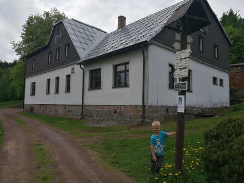 Leon przy drogowskazach obok białego domu na polanie